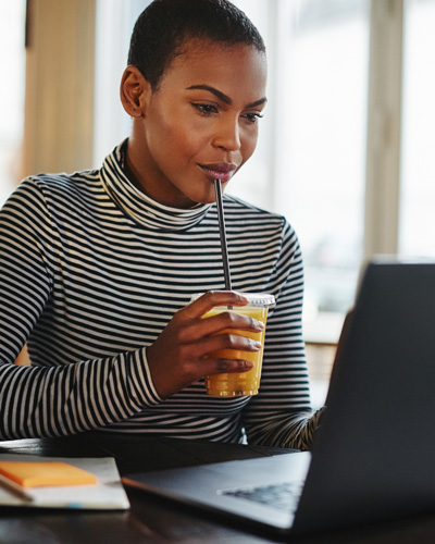 A young woman sipping on a smoothie while she works