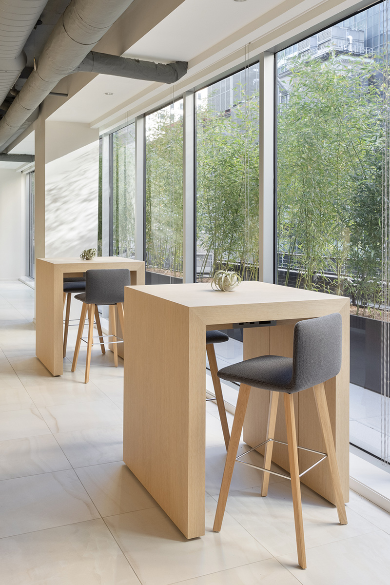 Tall, natural wood work benches next to floor to ceiling windows