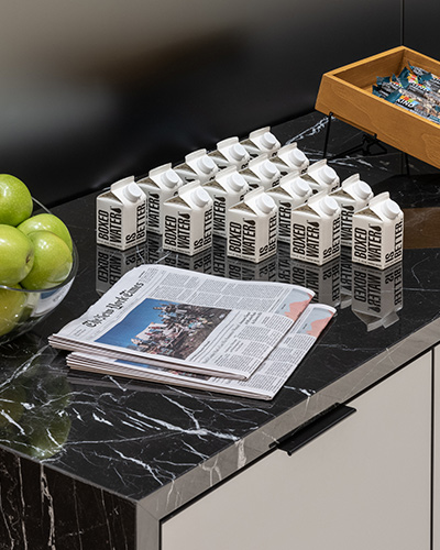 A stack of New York Time newspapers on a black marble countertop